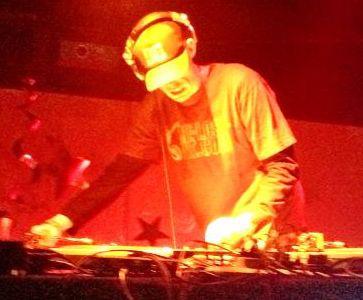 DJ Natural Nate® performing under red stage lights, Scratch Live setup